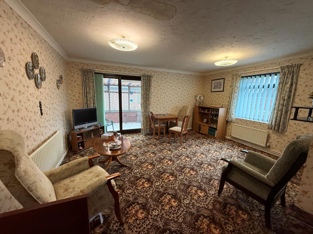 Lot: 102 - TWO-BEDROOM BUNGALOW IN NEED OF IMPROVEMENT - Lounge with window and doors going into conservatory